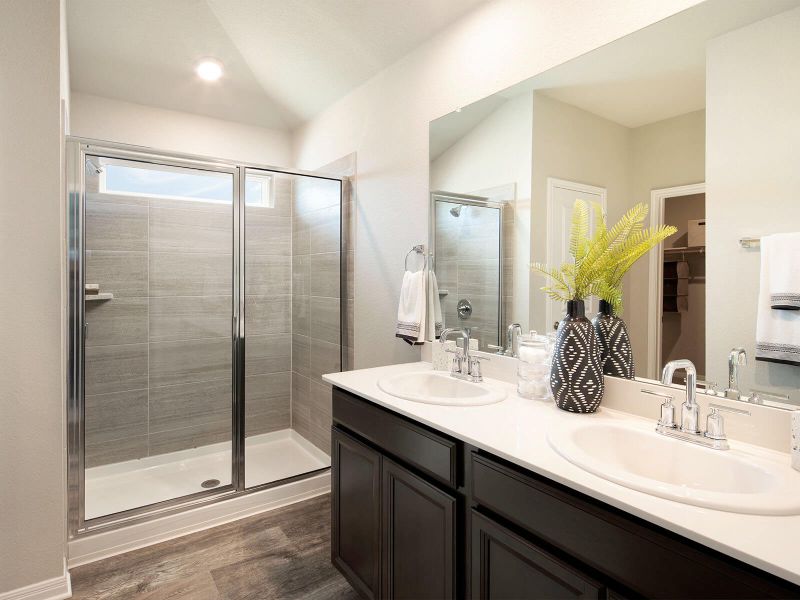Dual sinks and a spacious walk-in shower create a spa-like primary bath.