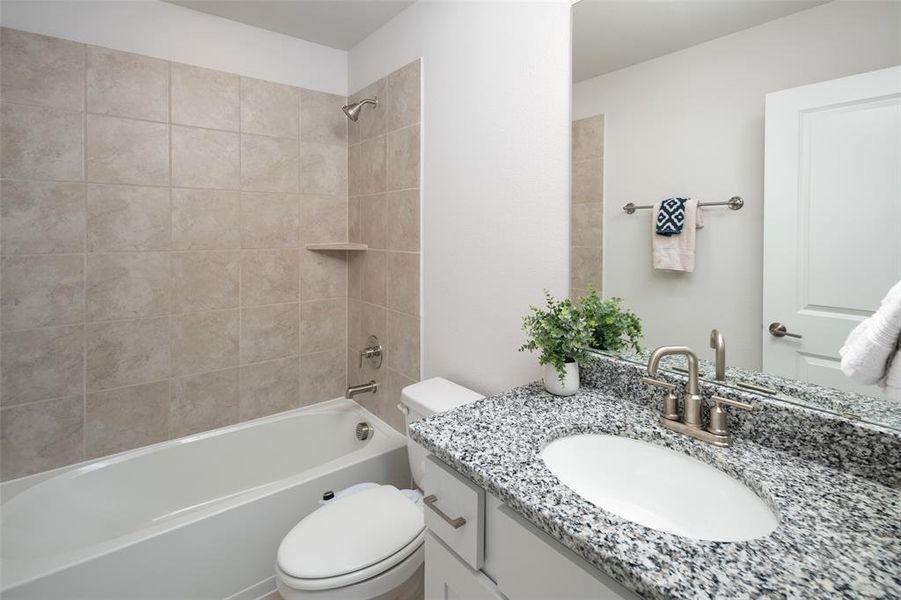 Full bathroom with tiled shower / bath combo, vanity, and toilet