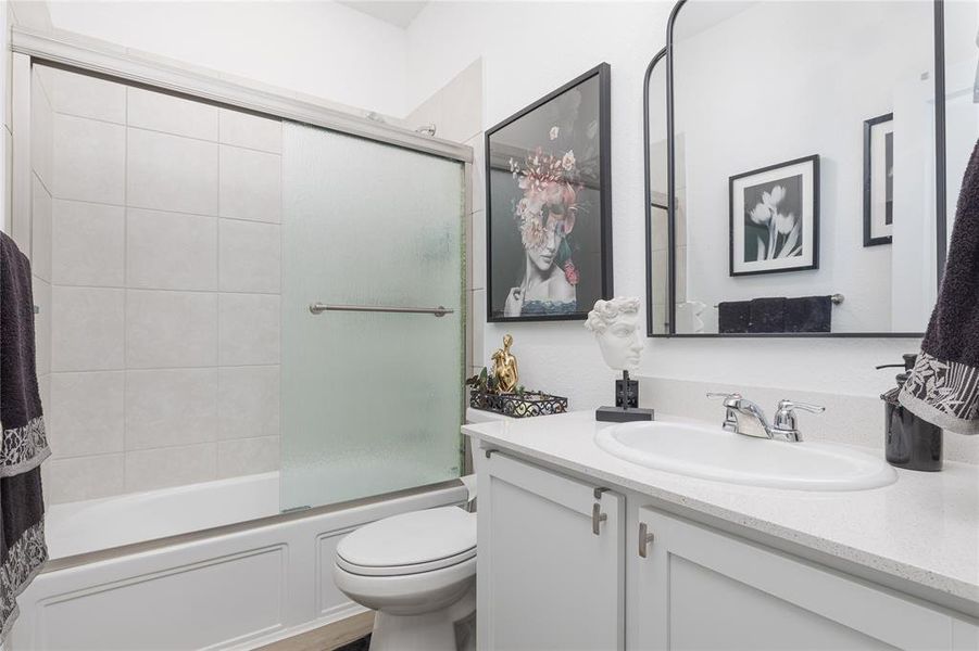 Full bathroom with shower / bath combination with glass door, vanity, and toilet