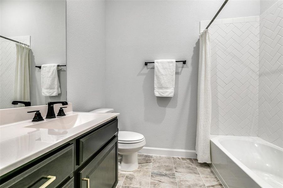 Full bathroom with toilet, vanity, and shower / bathtub combination with curtain