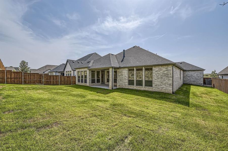 Rear view of property featuring a lawn and a patio area