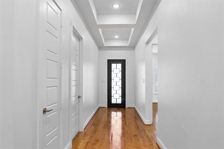 Foyer with light hardwood / wood-style flooring and a tray ceiling