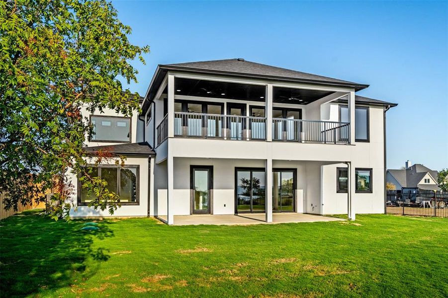 Back of house featuring a yard, ceiling fan, a balcony, and a patio area