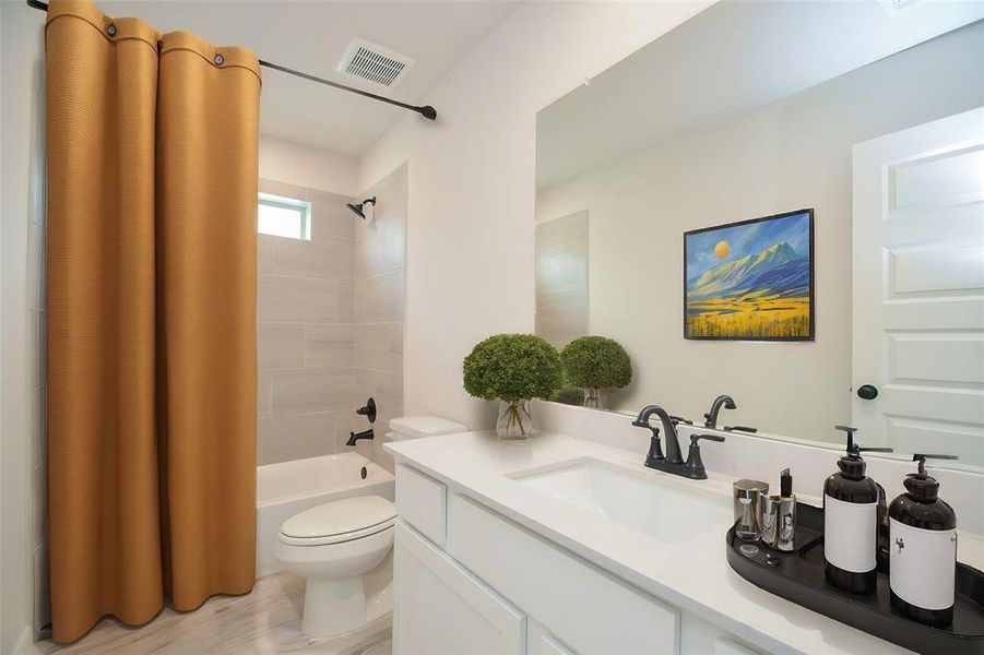 A clean and contemporary bathroom featuring a full tub with tiled surround, modern fixtures, and a vanity with a quartz countertop. The soft neutral tones create a spa-like atmosphere, ideal for relaxing after a long day.