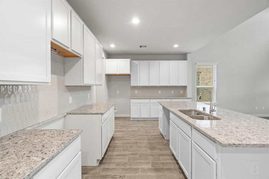 The kitchen is a culinary haven, featuring granite countertops, a tile backsplash, stainless steel appliances, 42” upper cabinets, and recessed lighting. Sample photo of completed home with similar floor plan. As-built interior colors and selections may vary.