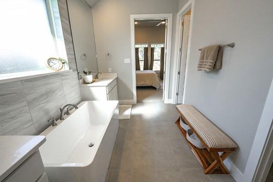 Bathroom featuring a bath, tile walls, vanity, and tile patterned floors