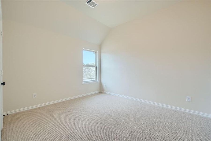 Empty room with vaulted ceiling and carpet floors