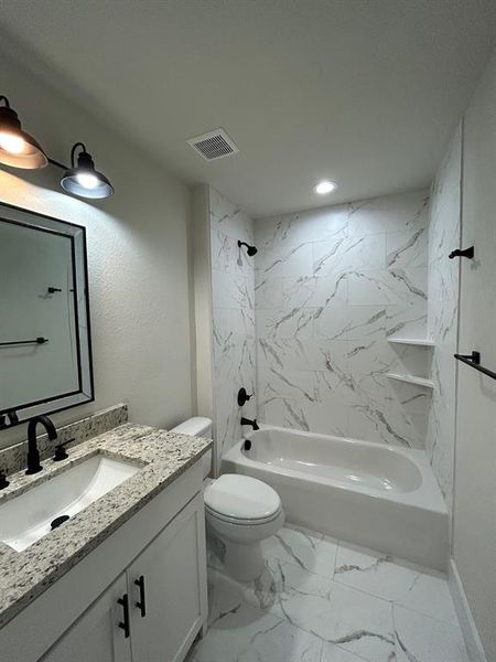 Primary bathroom, with tiled shower/bath combo, vanity, and tiled flooring