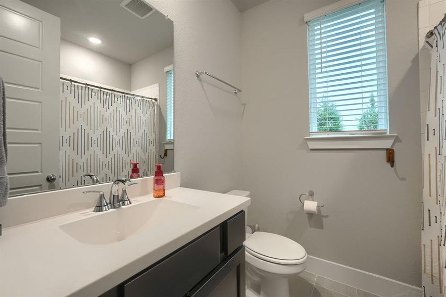 Bathroom with a shower with shower curtain, tile patterned flooring, vanity, and toilet