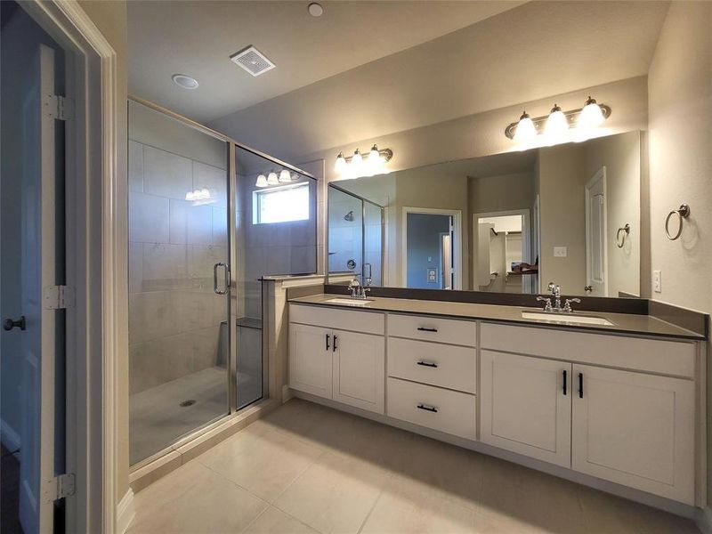 Bathroom featuring vanity, a shower with shower door, and tile patterned flooring