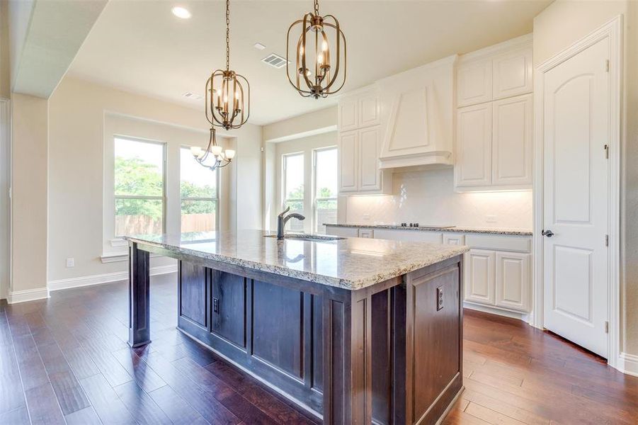 Kitchen featuring white cabinetry, custom exhaust hood, a kitchen island with sink, and dark hardwood / wood-style flooring