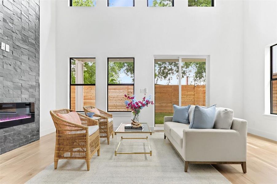 Living room with light hardwood / wood-style flooring, a stone fireplace, and a healthy amount of sunlight