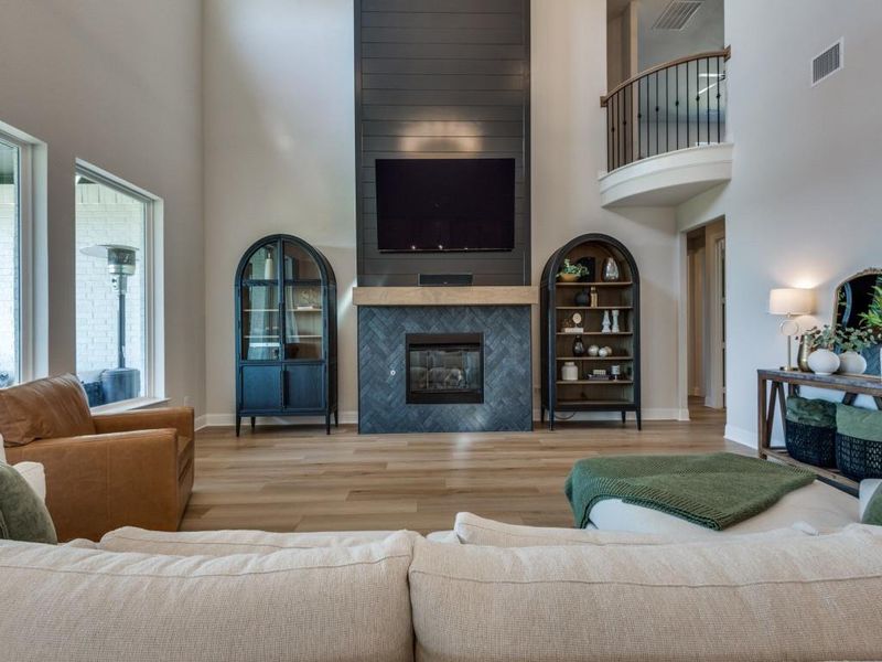 Living room featuring light hardwood / wood-style flooring, a fireplace, and a towering ceiling