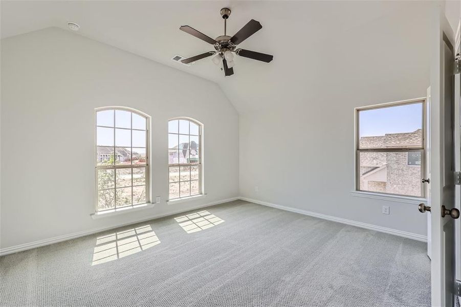 Carpeted empty room with lofted ceiling and ceiling fan