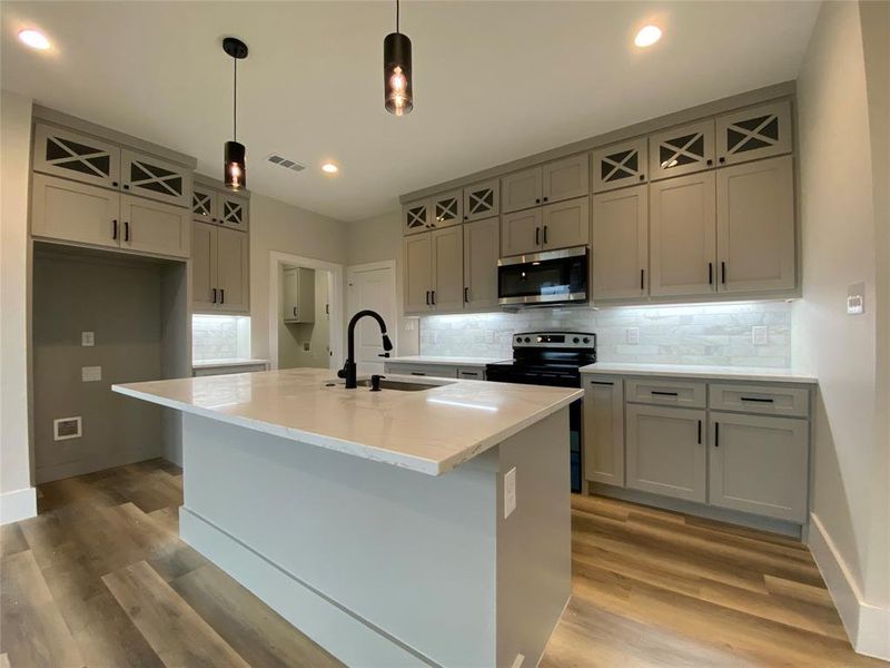 Kitchen featuring a center island with sink, stainless steel appliances, sink, and light wood-type flooring