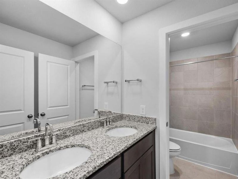 he upstairs hallway bathroom includes double sinks with granite countertops and a convenient tub-shower combo, offering a stylish and functional space for daily use.