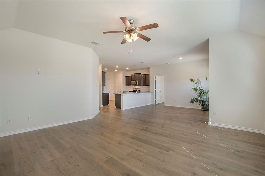 Unfurnished living room featuring lofted ceiling, ceiling fan, and dark hardwood / wood-style flooring