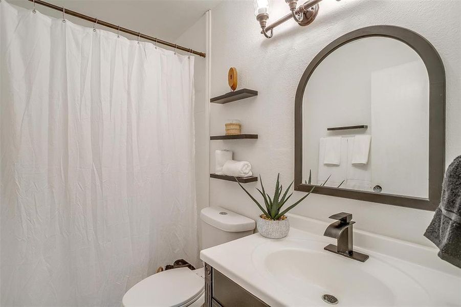 Bathroom featuring vanity, toilet, and curtained shower