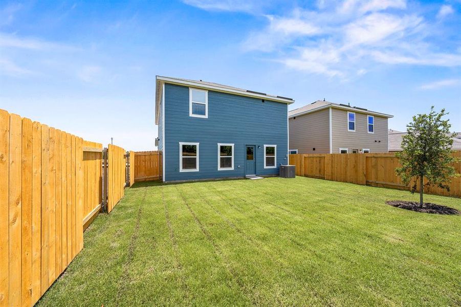 Rear view of property featuring a lawn and central air condition unit