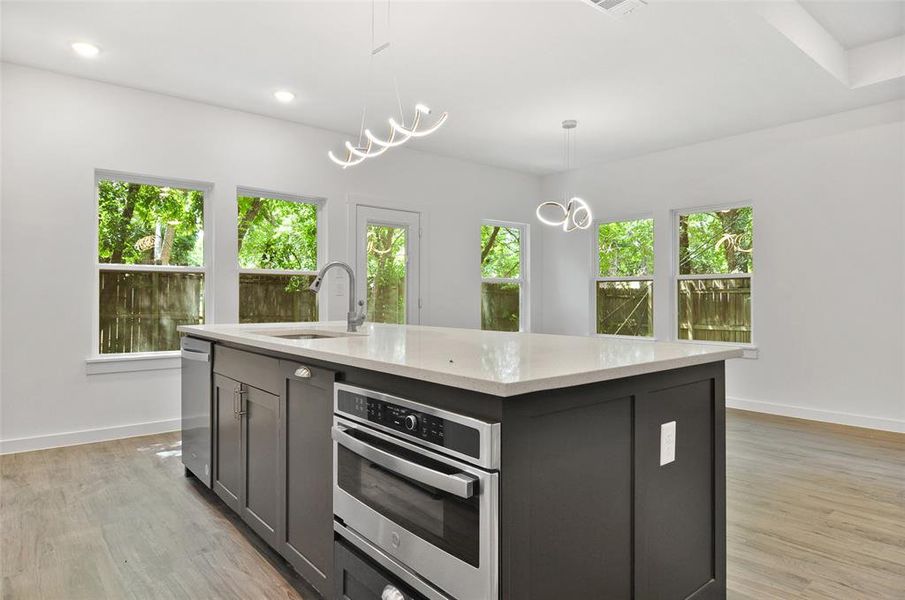 Kitchen featuring a notable chandelier, light hardwood / wood-style flooring, stainless steel appliances, pendant lighting, and sink