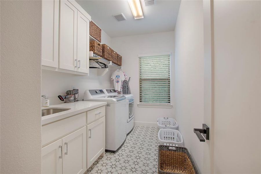 Laundry area with cabinets, sink, light tile floors, and washing machine and clothes dryer