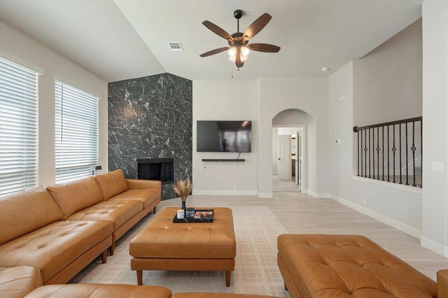 Spacious living room features ceiling fan, tiled fireplace, and engineered wood floors. Arched doorway leads into the primary bedroom.