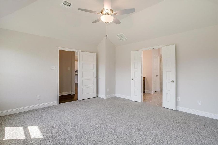 Unfurnished bedroom featuring ceiling fan, light colored carpet, and vaulted ceiling