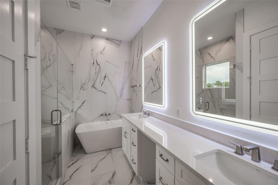 The luxurious bath in the primary retreat has tile accent walls, a relaxing tub and oversized shower.