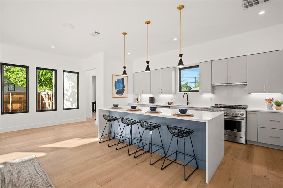 The home chef will love all of the desirable modern features including sleek stainless appliances with a high-end gas range, built-in microwave on the island, dishwasher, and wine fridge.