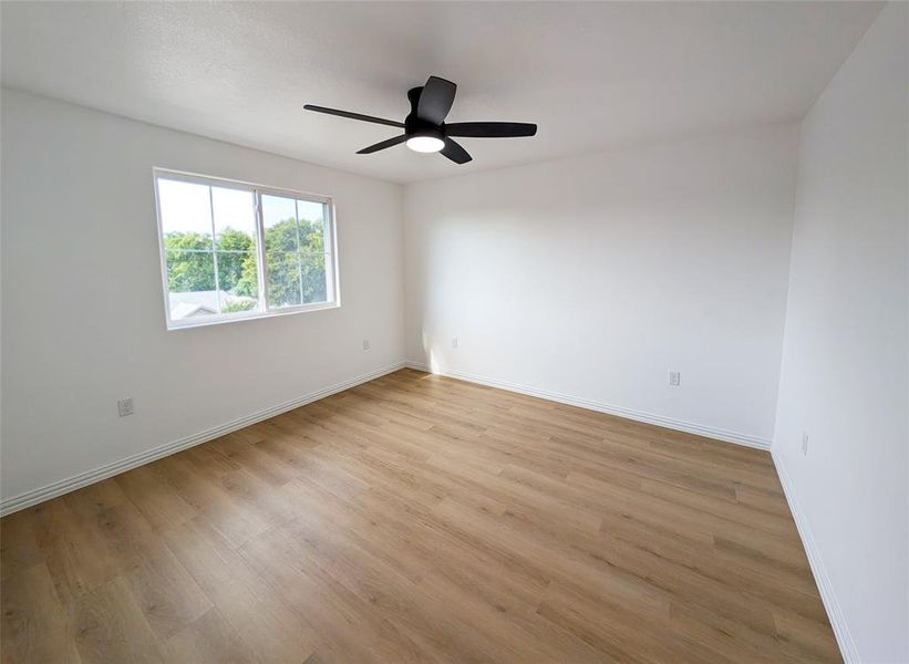 Empty room with ceiling fan and light wood-type flooring