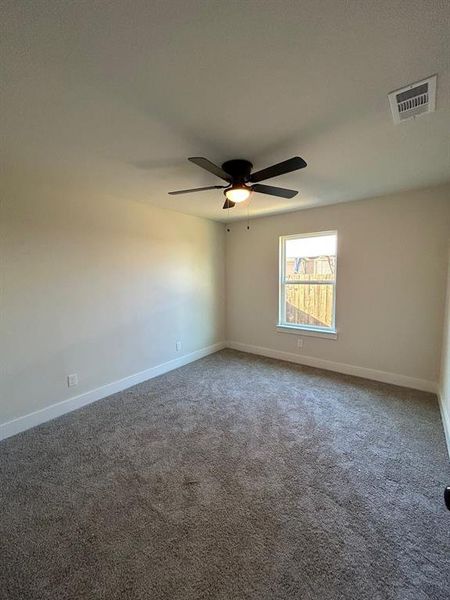 Secondary bedroom with ceiling fan and carpet