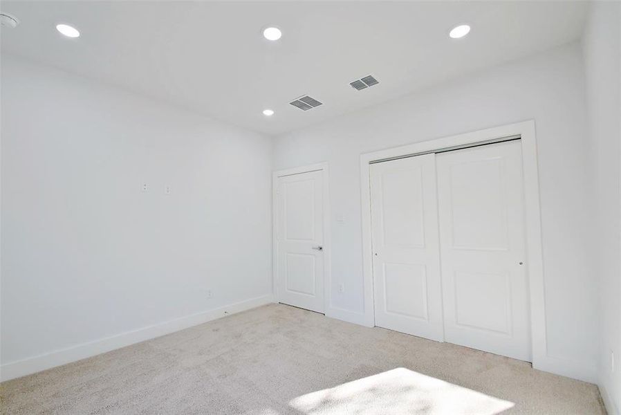 Unfurnished bedroom featuring light carpet and a closet