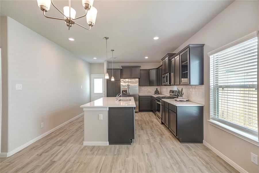 This  modern, open-concept kitchen equipped with stainless steel appliances, ample cabinet space, and sleek countertops. It seamlessly flows into a spacious living area, perfect for entertaining or family gatherings.