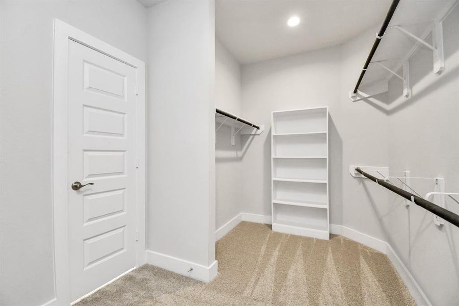 Immerse yourself in the lap of luxury within this roomy walk-in closet boasting high ceilings and plush carpeting.