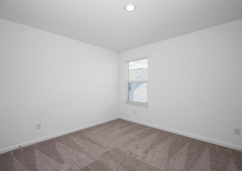 Secondary bedroom with tan carpet and a window.