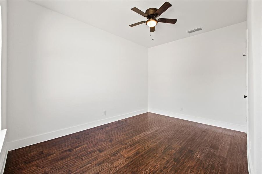 Empty room featuring dark wood-type flooring and ceiling fan