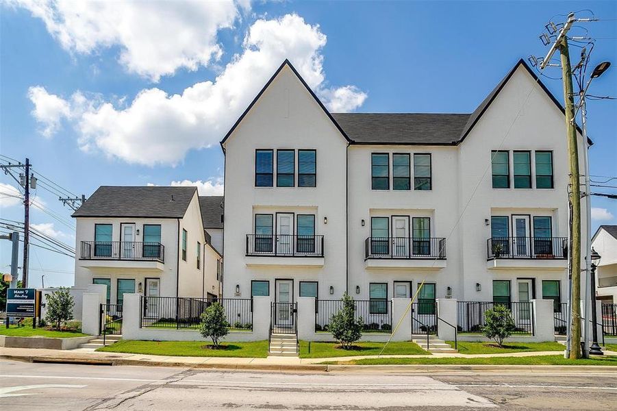 A stunning luxury townhome featuring a modern architectural design stands proudly, showcasing a beautifully landscaped, private gated front yard.