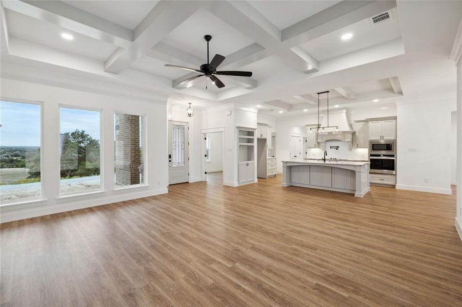 Unfurnished living room with ceiling fan, sink, beam ceiling, coffered ceiling, and light hardwood / wood-style flooring