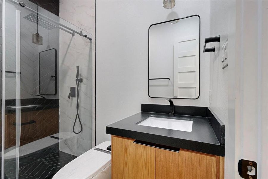 Bathroom featuring a shower with door, vanity, and toilet