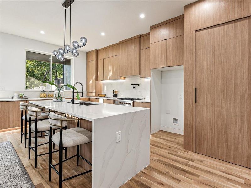 Kitchen featuring pendant lighting, an island with sink, light wood-type flooring, and sink