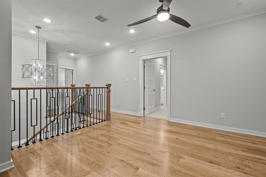 Loft living area 2nd floor. crown molding, light hardwood / wood-style flooring, and ceiling fan with notable chandelier