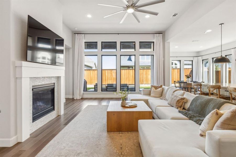 Living room with dark wood-type flooring, ceiling fan, and a healthy amount of sunlight