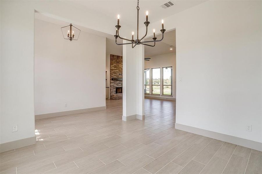 Empty room with a notable chandelier, light hardwood / wood-style flooring, and a fireplace