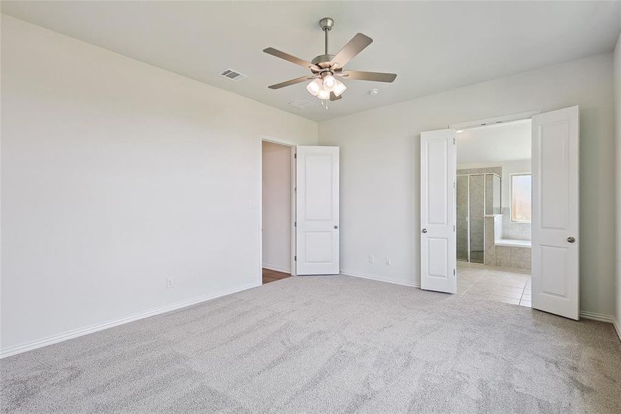 Unfurnished bedroom featuring light carpet, connected bathroom, and ceiling fan