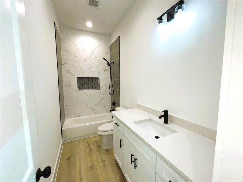 Full bathroom featuring vanity, toilet, wood-type flooring, and tiled shower / bath