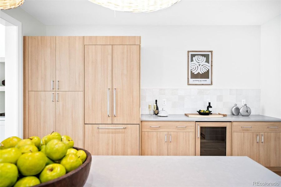 Discrete refrigerator blends in to abundant cabinet storage and dedicated dry bar w/ bar fridge