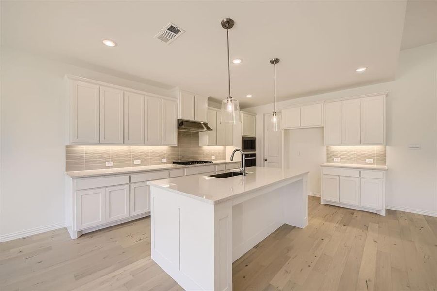 Kitchen featuring white cabinets, backsplash, light hardwood / wood-style flooring, and wall chimney exhaust hood