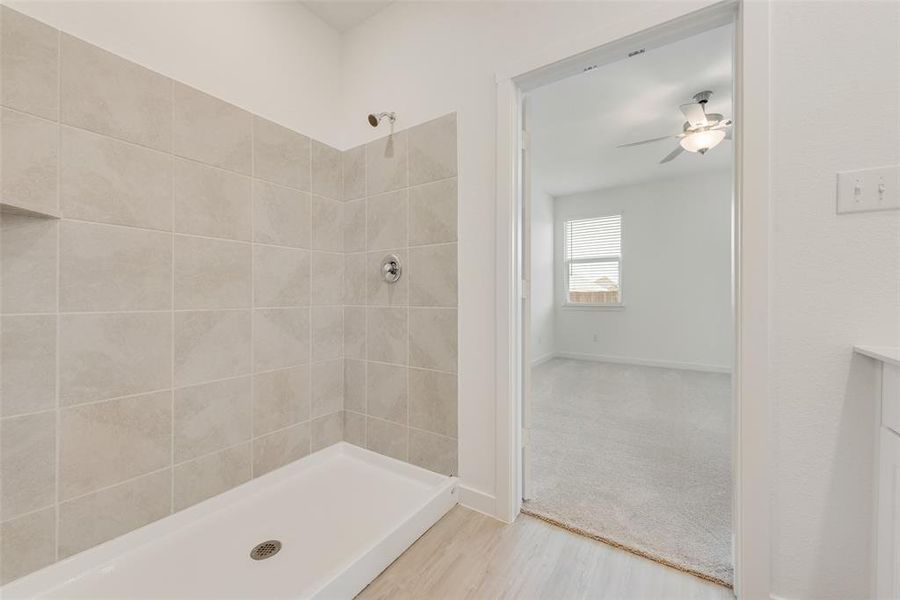 Bathroom featuring wood-type flooring, vanity, a tile shower, and ceiling fan