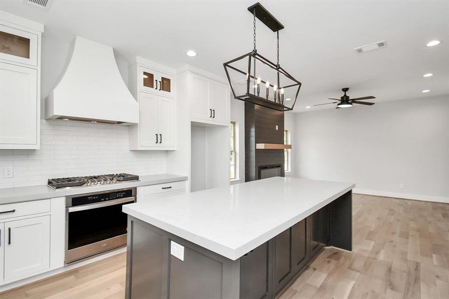 The oversized kitchen island accommodates seating for four, and we love the designer lighting fixture placed above it!