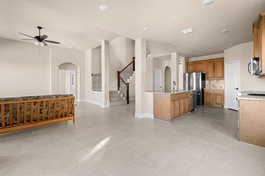 Kitchen featuring light tile patterned floors, ceiling fan, light stone counters, and stainless steel appliances